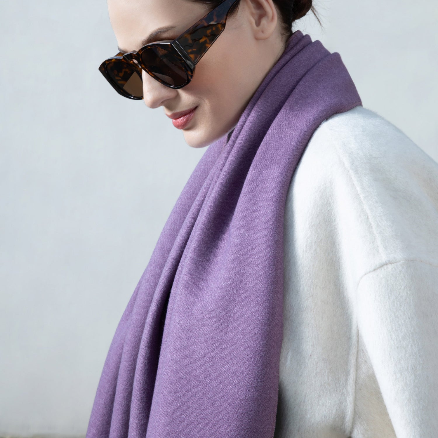 Person wearing a purple scarf and sunglasses against a plain background
