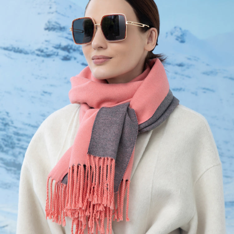 Woman wearing a pink and gray scarf with sunglasses against a blue water background