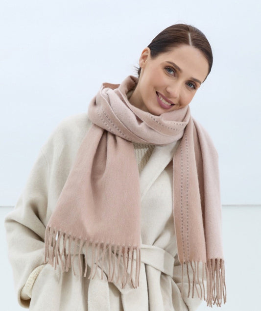 Woman wearing a pink scarf and beige coat on a light background