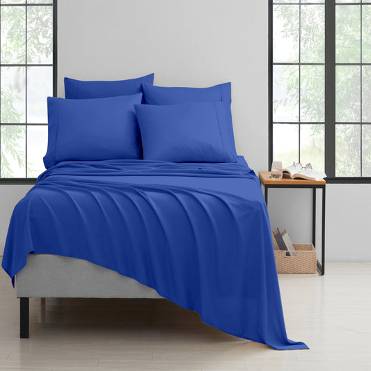 Blue bedding set on a bed in a room with large windows.