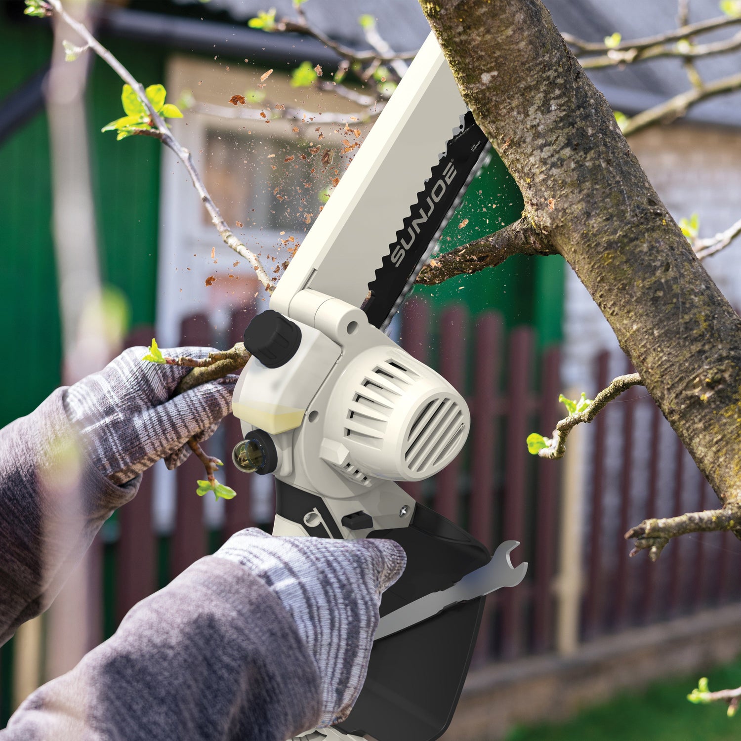 Person using a chainsaw to cut a branch with a blurred background