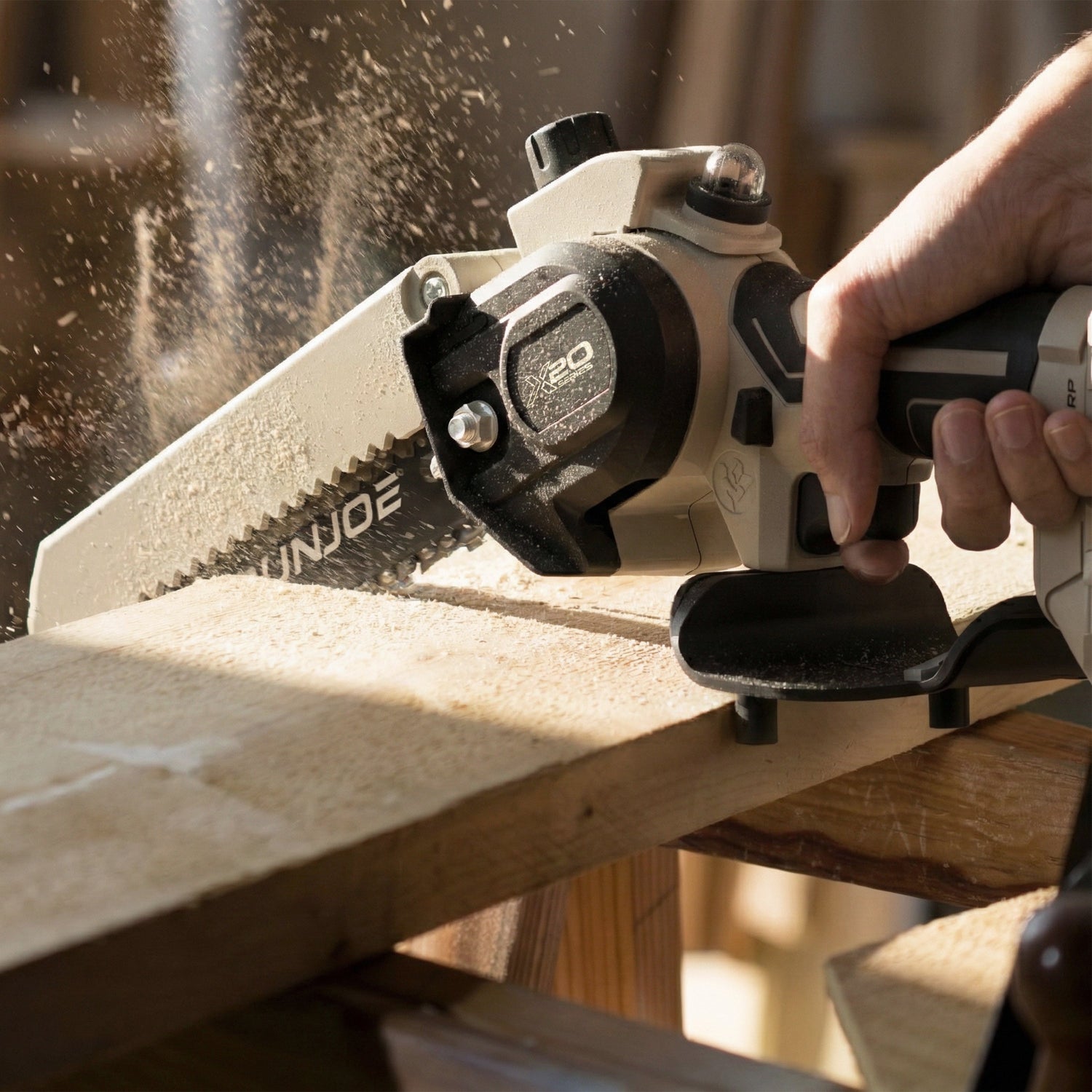Person using a Einjoe power tool on a wooden surface with sawdust in the air.