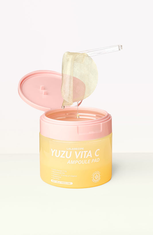 A jar of Calaulove Yuzu Vita C Ampoule Pad with a pink lid and yellow body, shown open with a translucent pad being lifted out on a clear applicator against a clean white background.