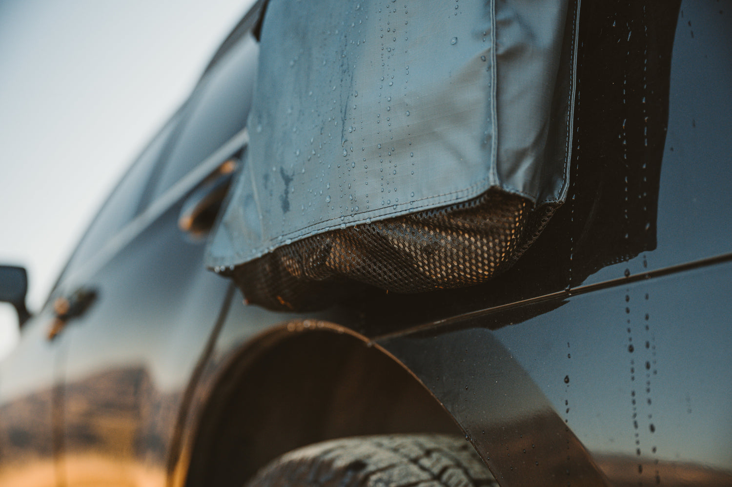 Close-up of a vehicle's side mirror and tire with a blurred background
