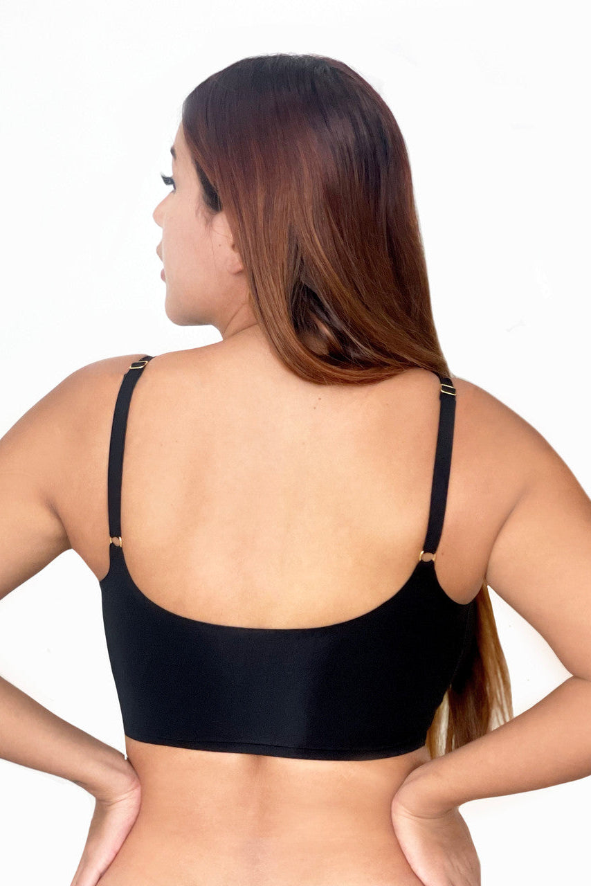 Woman wearing a black bra against a white background. The back of the bra is displayed.