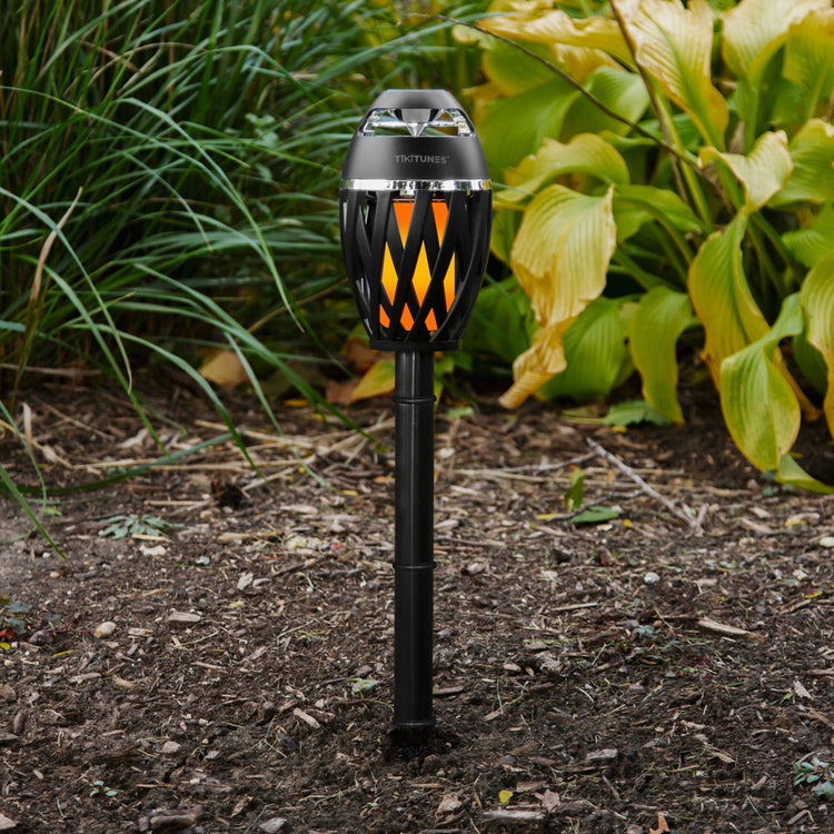 Solar-powered garden lamp with flame design on a garden path