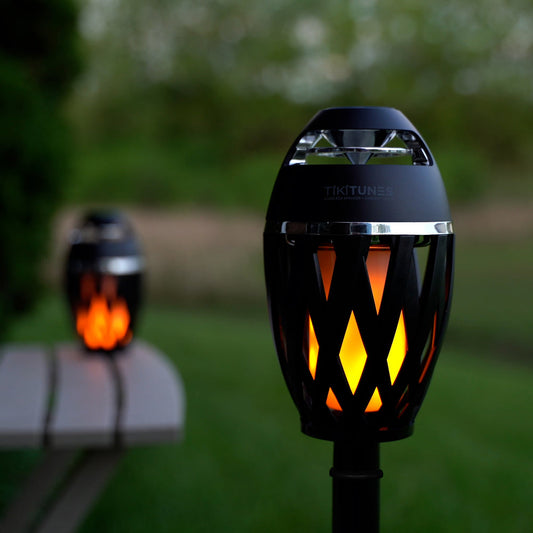 Black and orange outdoor speaker with TIKITUNES branding on a white background with music notes.