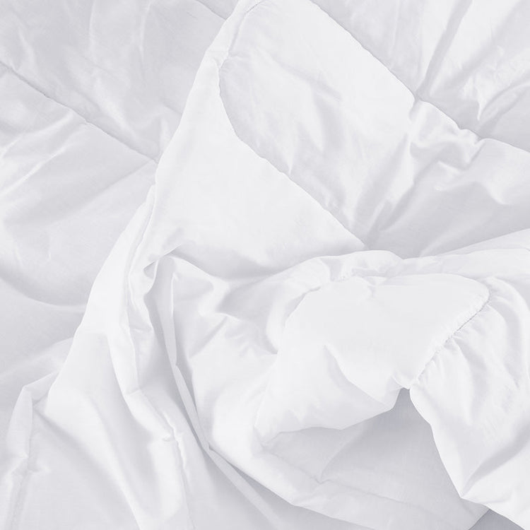 Close-up of a white quilted comforter with folds on a white background