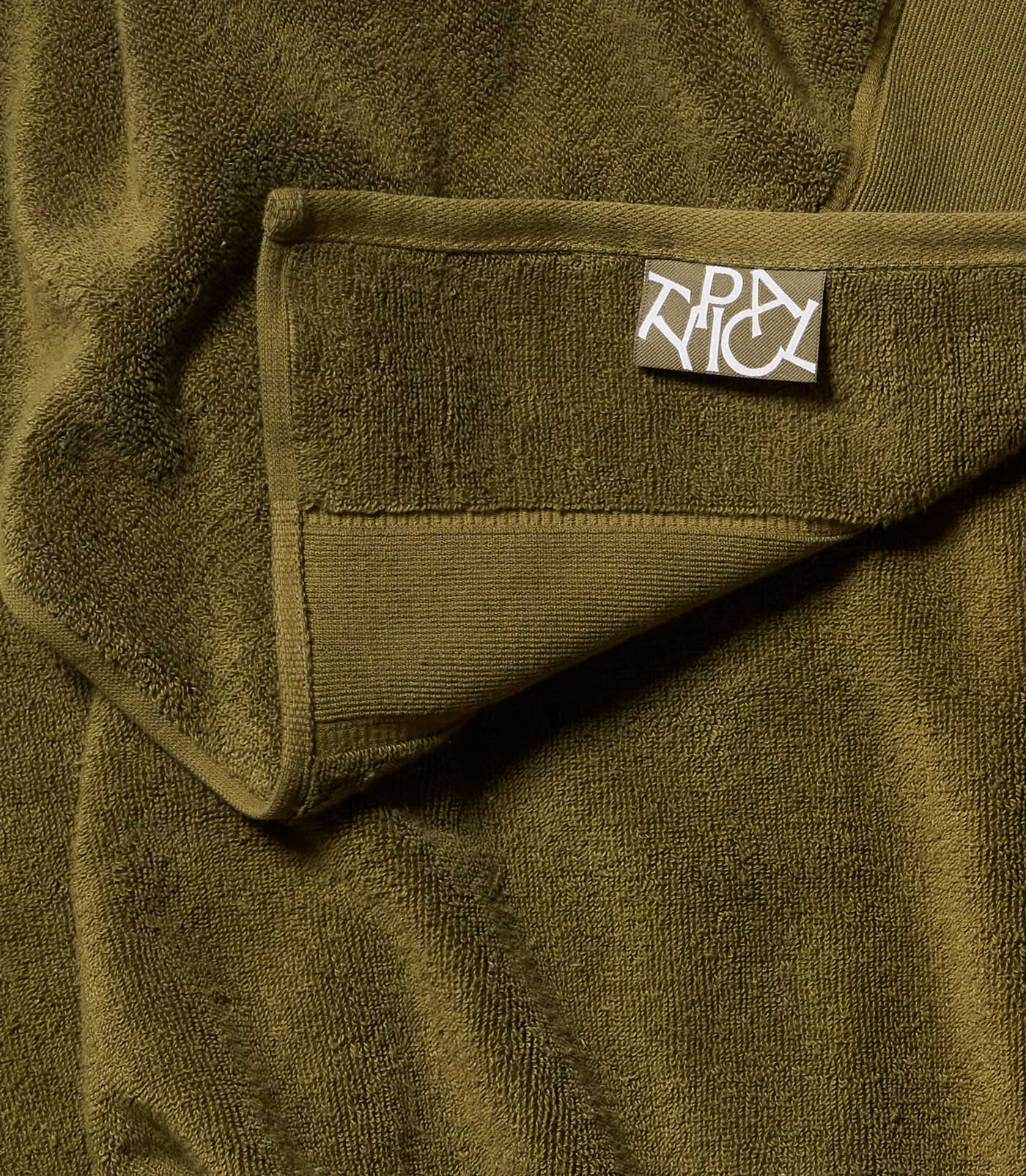 Close-up of a green towel with a brand label on it