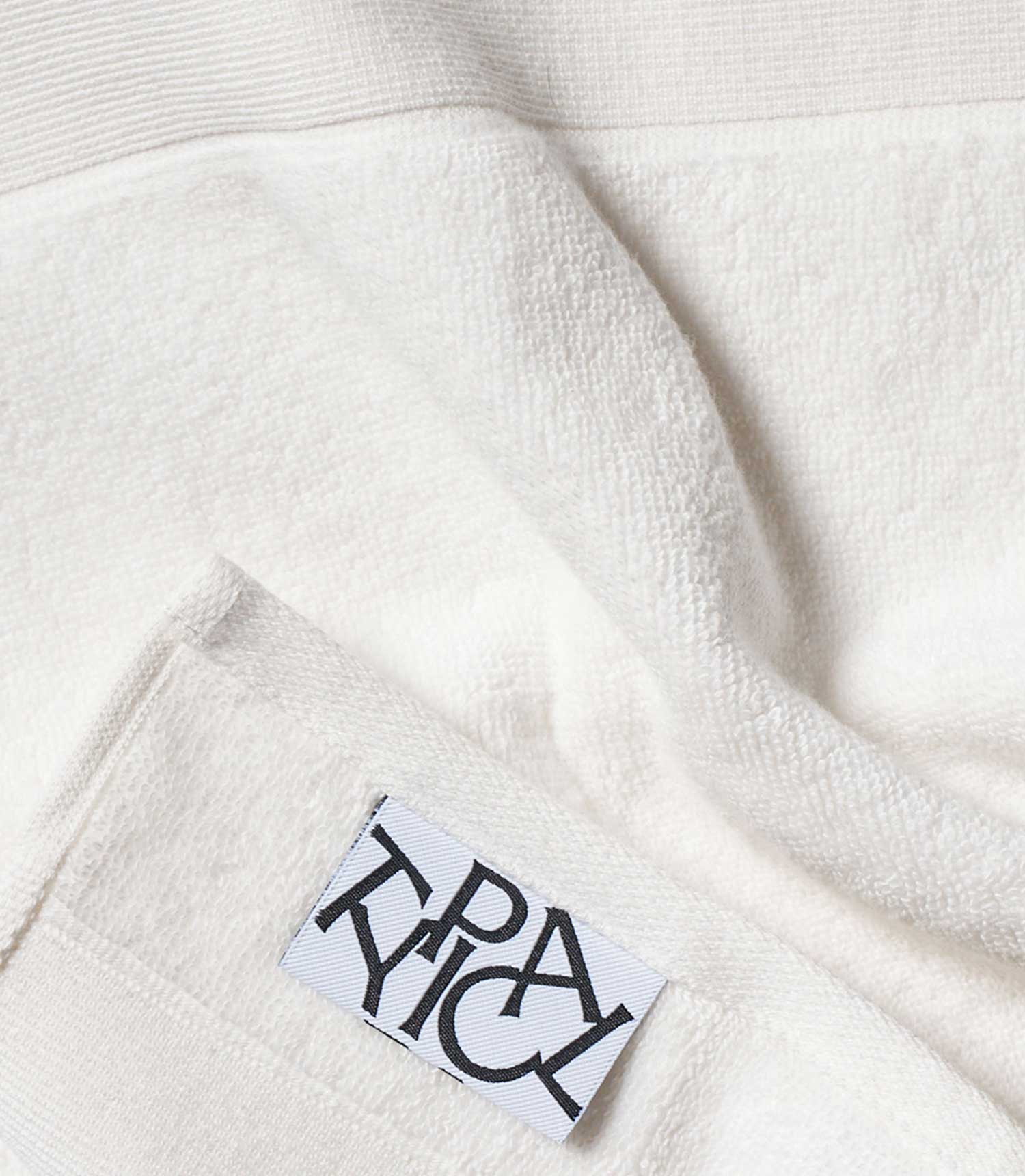 Close-up of a white garment with a brand label on a textured fabric background