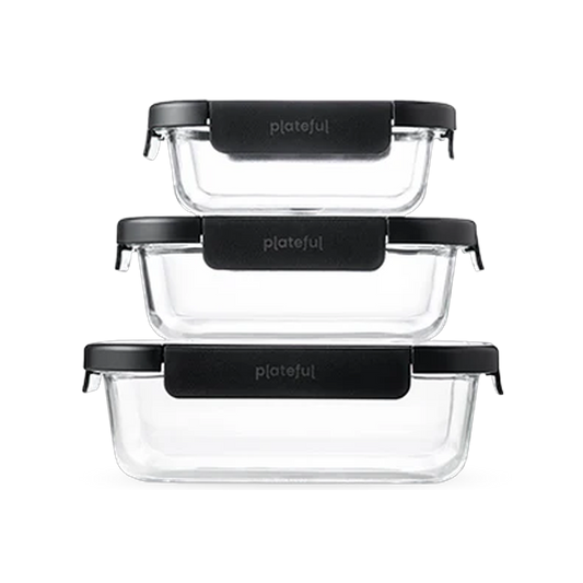 Set of three clear glass food containers with black lids on a white background
