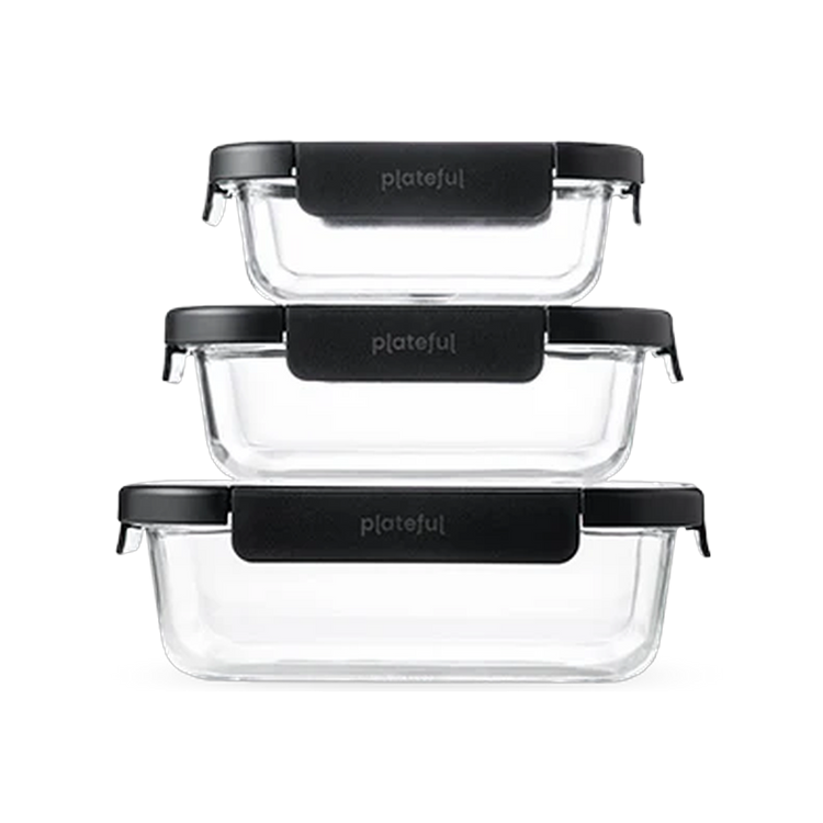 Set of three clear glass food containers with black lids on a white background