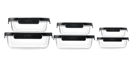 Set of three clear glass food containers with black lids on a white background