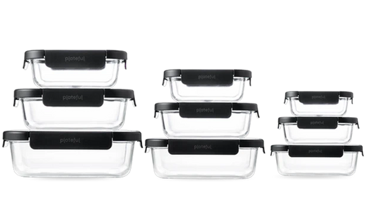 Set of three clear glass food containers with black lids on a white background