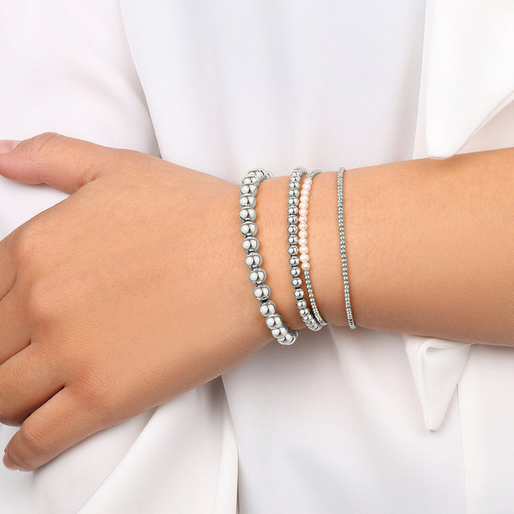 Close-up of a wrist wearing multiple silver beaded bracelets on a white background