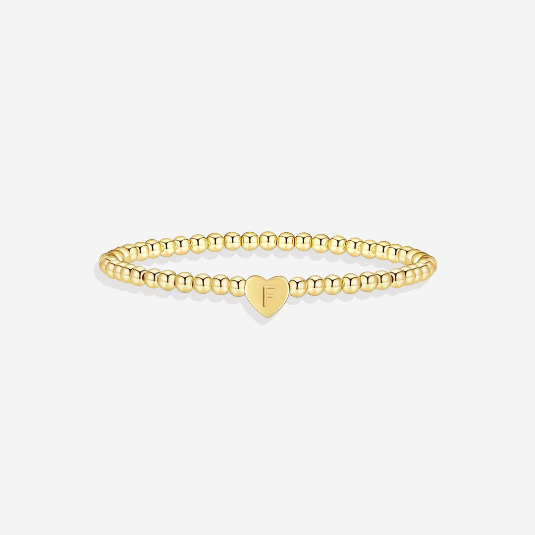 Gold bracelet with a heart-shaped charm on a white background