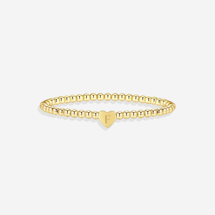 Gold bracelet with a heart-shaped charm on a white background
