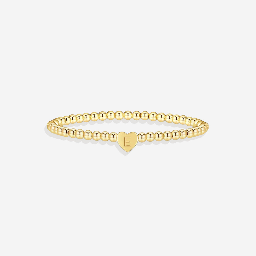 Gold bracelet with a heart-shaped charm on a white background