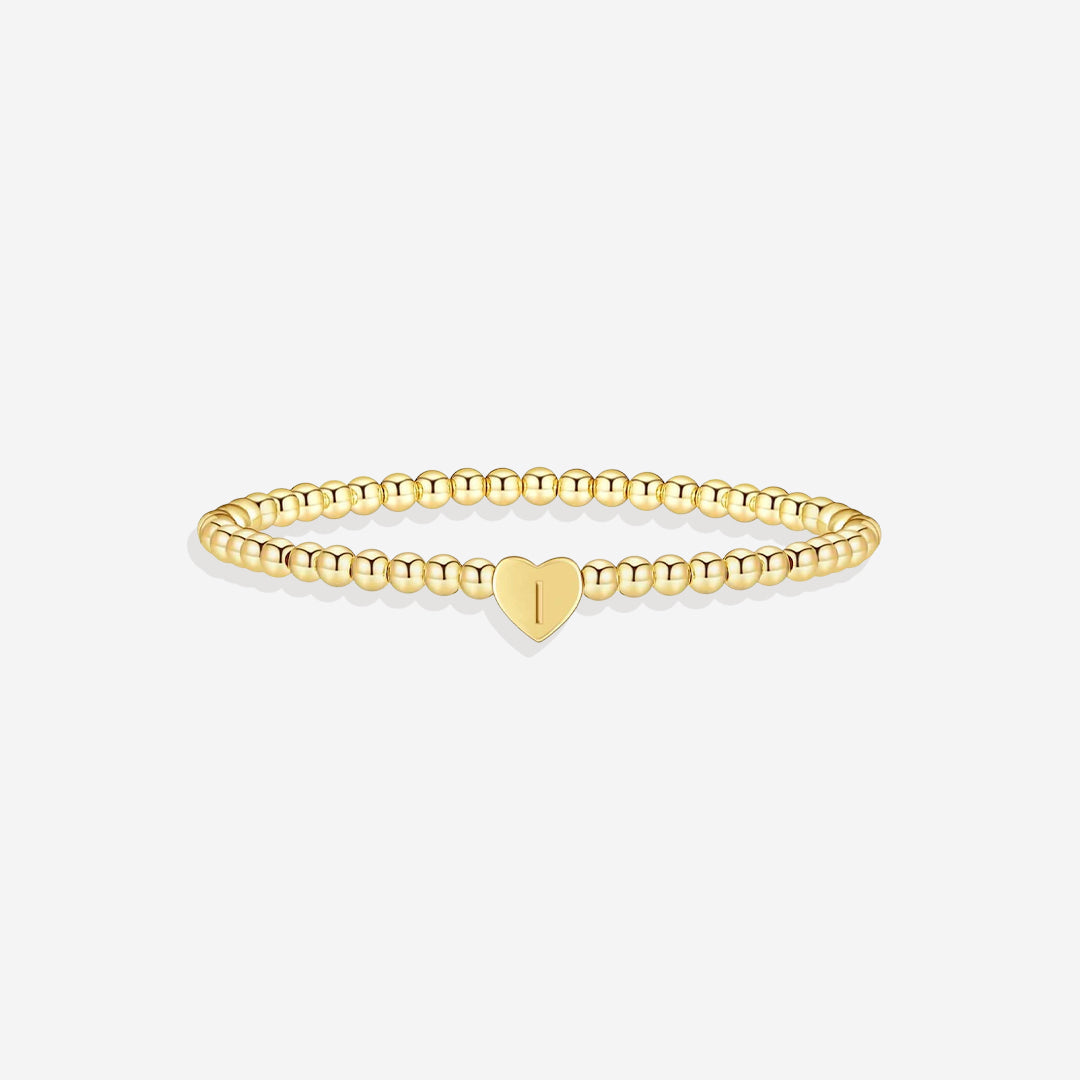 Gold bracelet with a heart charm on a white background