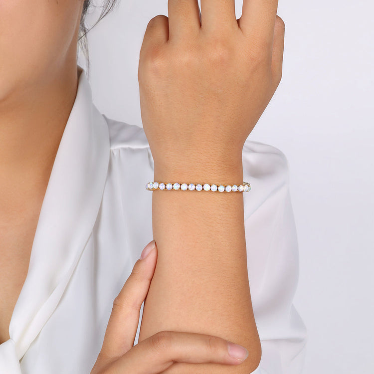Close-up of a hand wearing a pearl bracelet against a white background