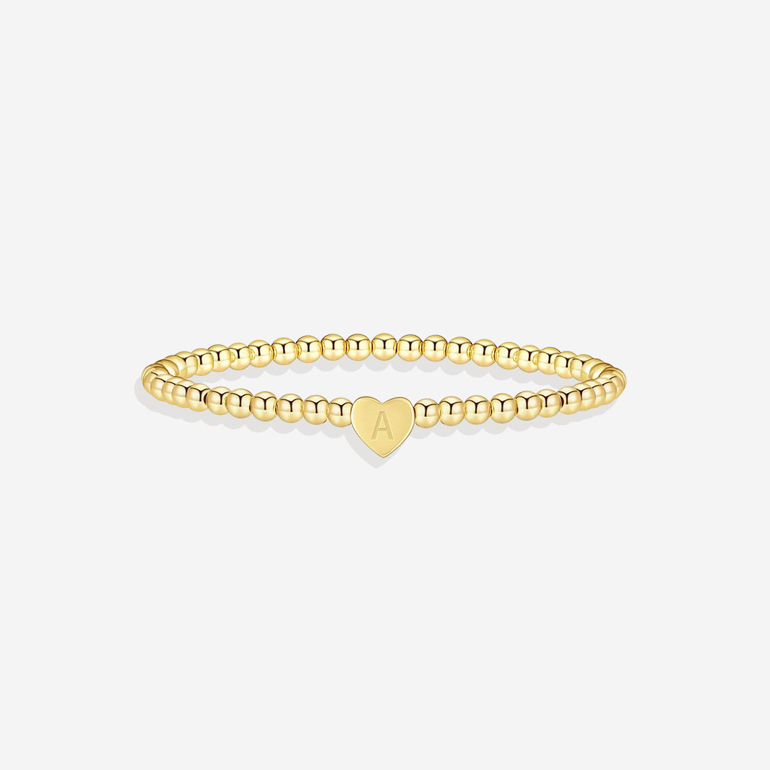 Gold bracelet with a heart-shaped charm on a white background