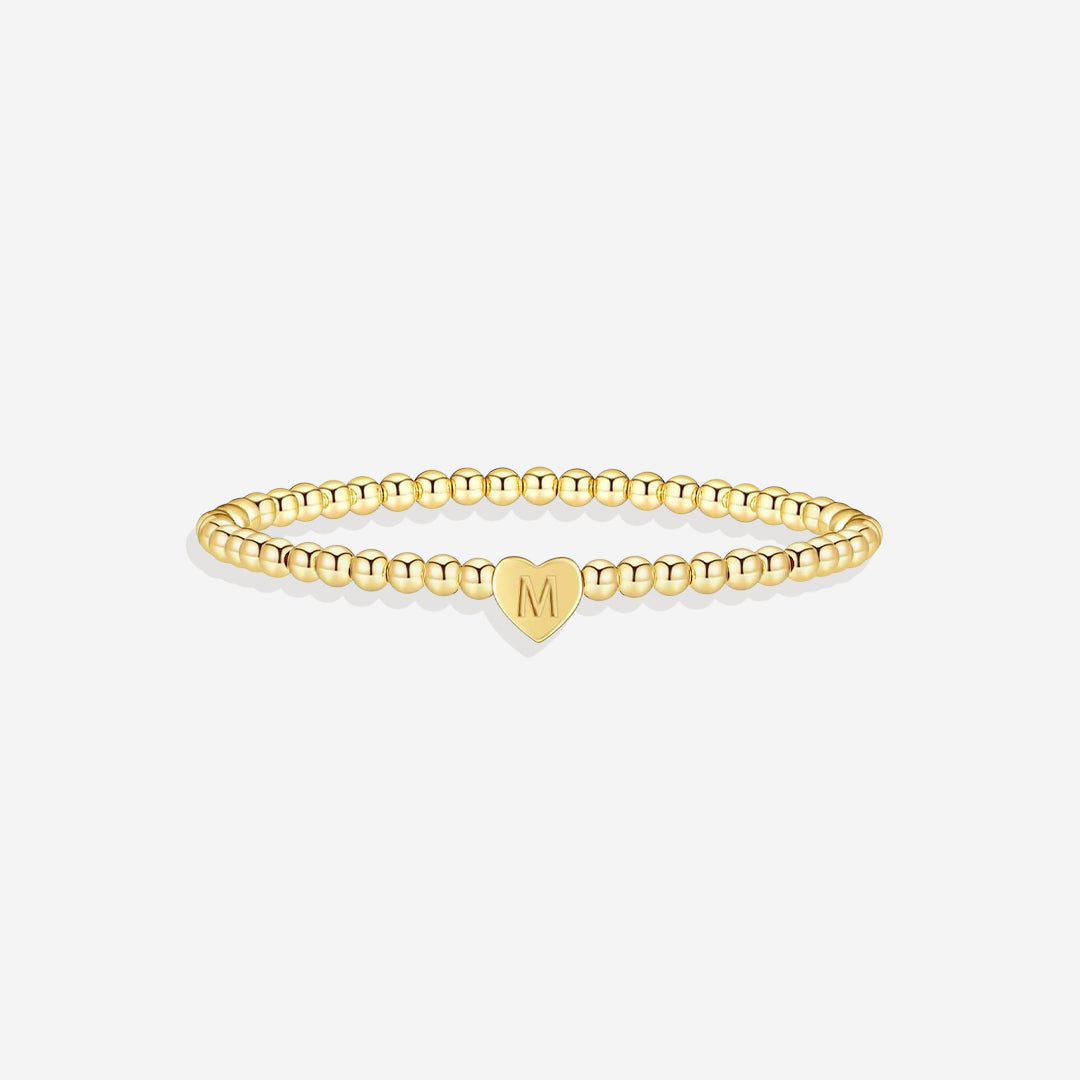 Gold bracelet with a heart-shaped charm on a white background