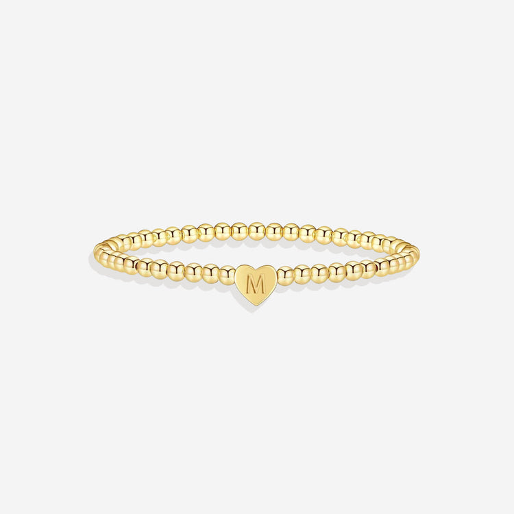 Gold bracelet with a heart-shaped charm on a white background