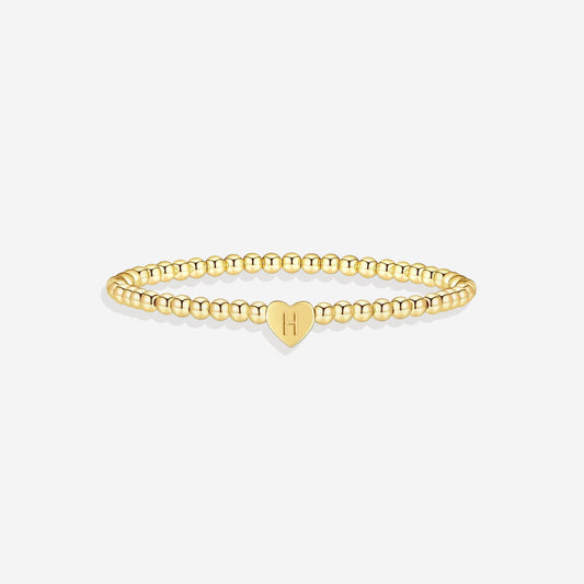 Gold beaded bracelet with a heart-shaped clasp on a white background