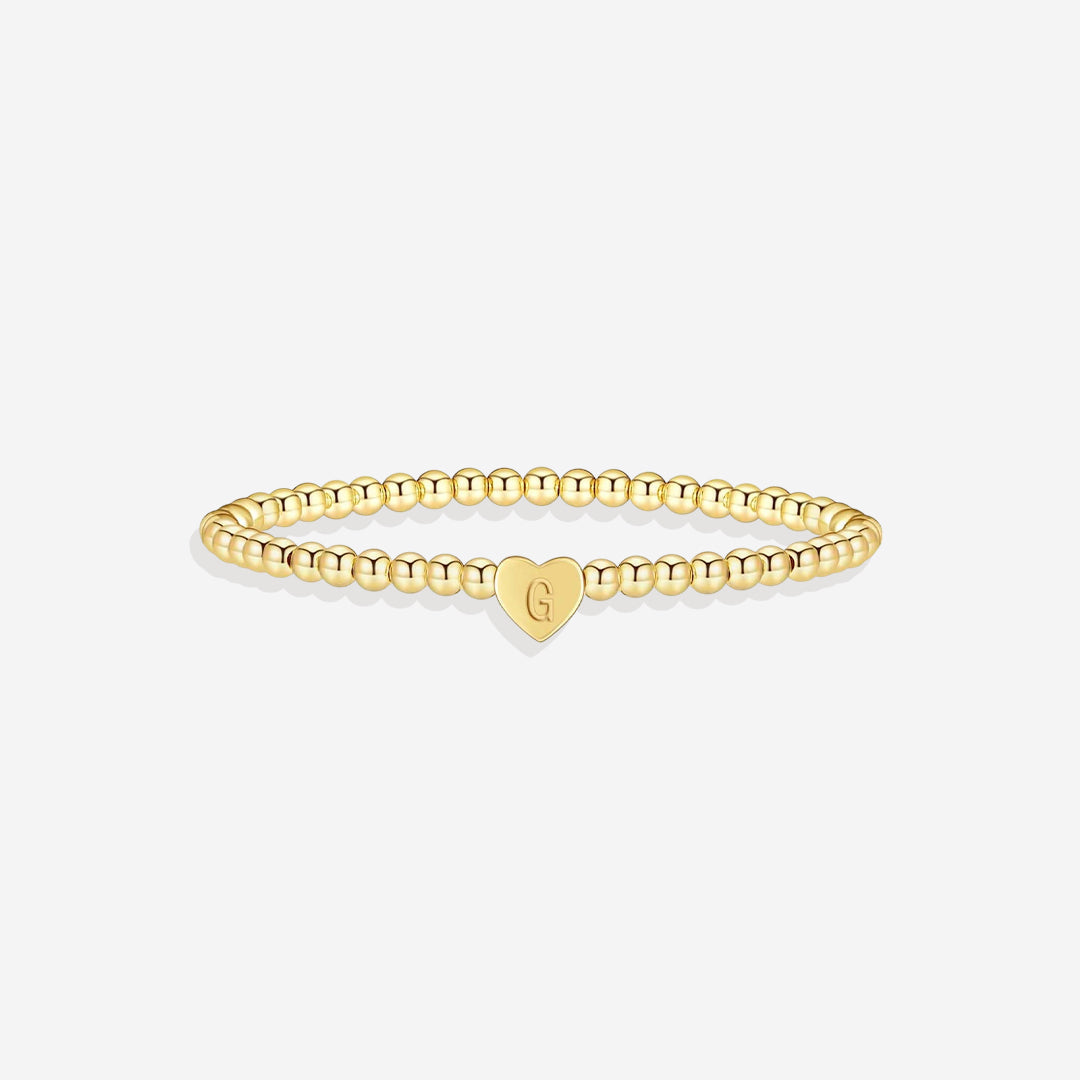 Gold bracelet with a heart-shaped charm on a white background
