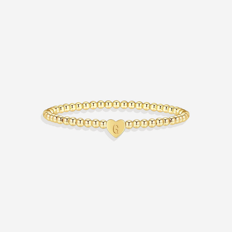 Gold bracelet with a heart-shaped charm on a white background