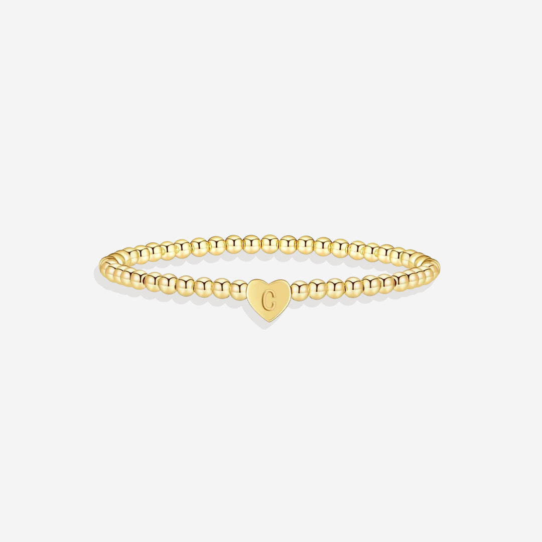 Gold bracelet with a heart-shaped tag on a white background