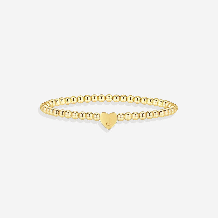 Gold bracelet with a heart-shaped charm on a white background