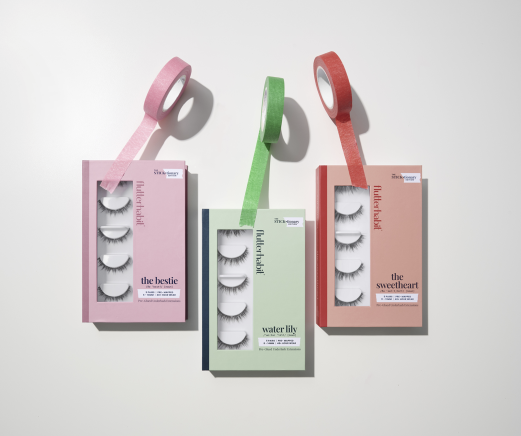 Three boxes of false eyelashes with colorful straps on a light gray background