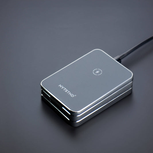 A foldable wireless charger stand with a smartphone, smartwatch, and earbuds being charged.