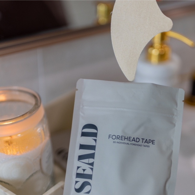 SEALD forehead tape package on a bathroom counter with a lit candle and mirror in the background