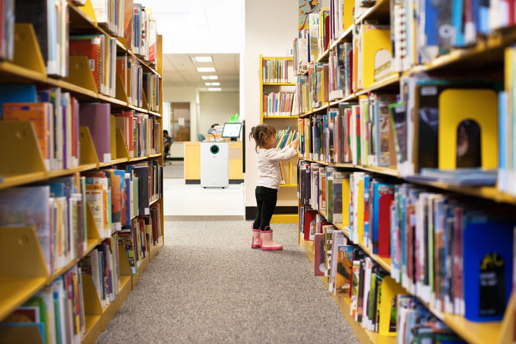 Child standing between bookshelves in a library