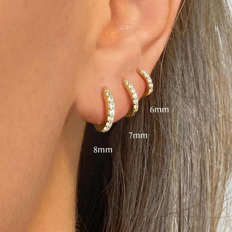 Gold hoop earrings displayed on an ear with size labels.
