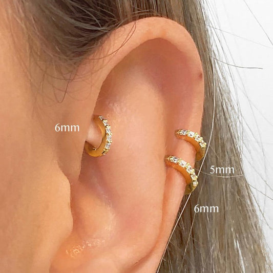 Gold hoop earrings with small diamonds on a white background