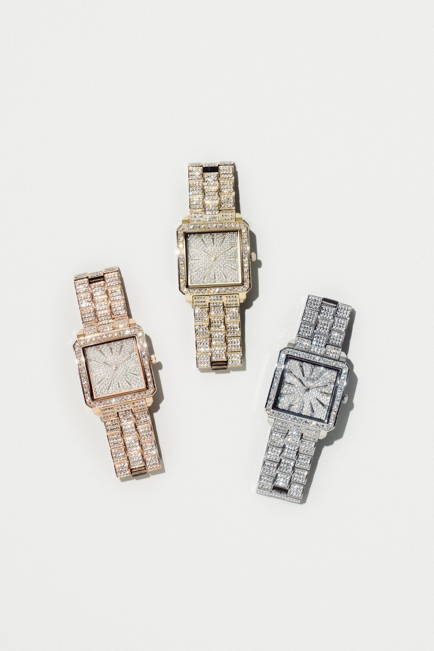Three luxury square-faced watches fully paved with diamonds, shown in rose gold, yellow gold, and silver-tone metal on a clean off-white background.
