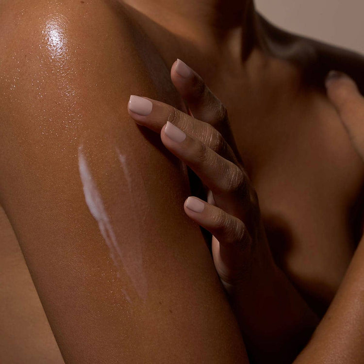 Hand applying sunscreen to a shoulder with a warm color tone