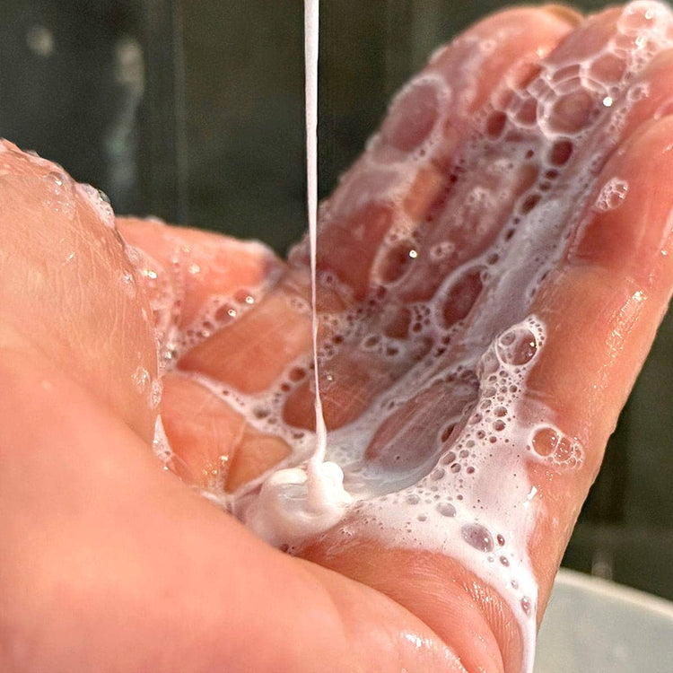 Foamy soap being lathered on hands with a blurred background