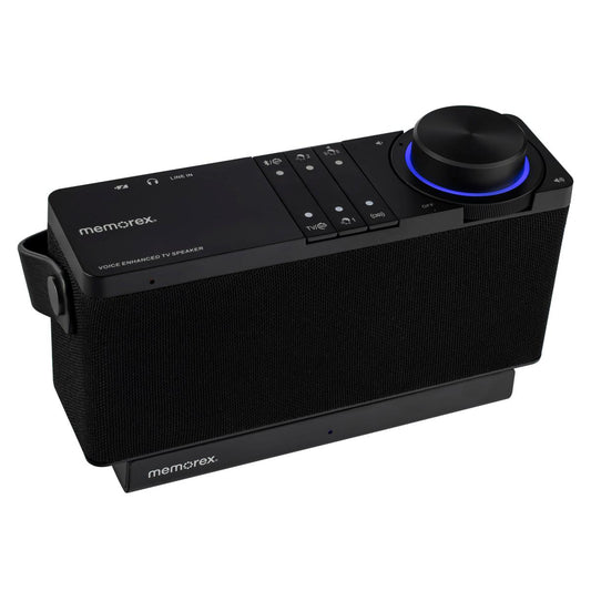 A black Memorex portable voice-activated TV speaker with a textured fabric grille, top control buttons, and a large rotary volume knob illuminated by a blue ring, shown on a plain white background.