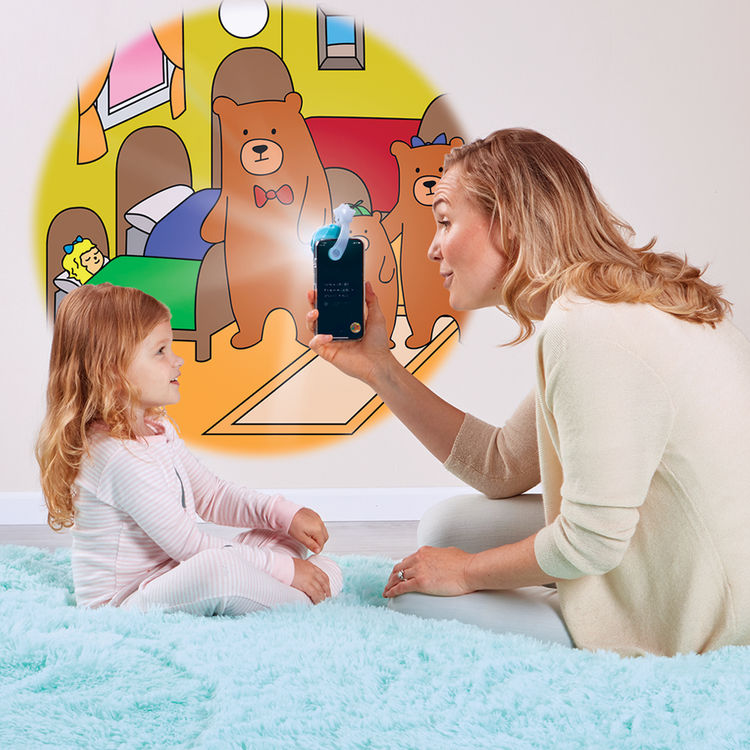 Woman and child playing with a device in front of a colorful bear-themed wall mural.