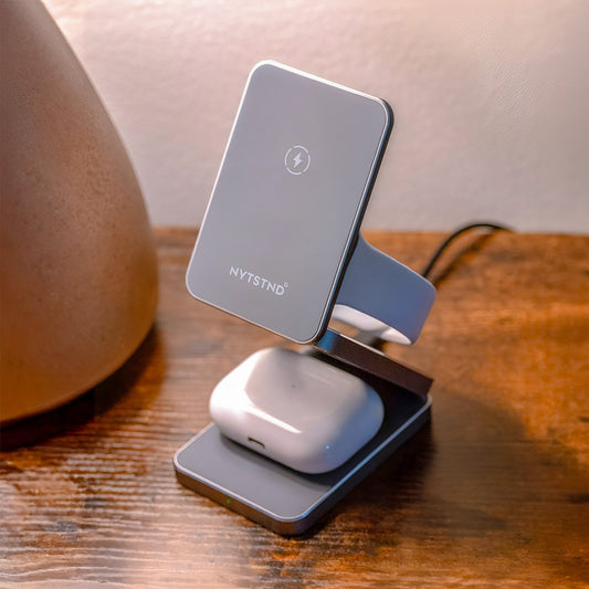 A foldable wireless charger stand with a smartphone, smartwatch, and earbuds being charged.