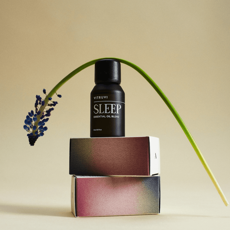 Vitruvi Sleep essential oil blend bottle on a beige background with lavender and a plant stem.