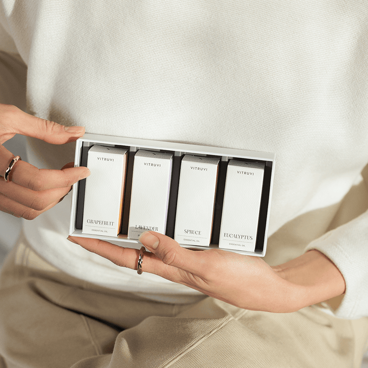 Person holding a set of Vitruvi skincare sample boxes.