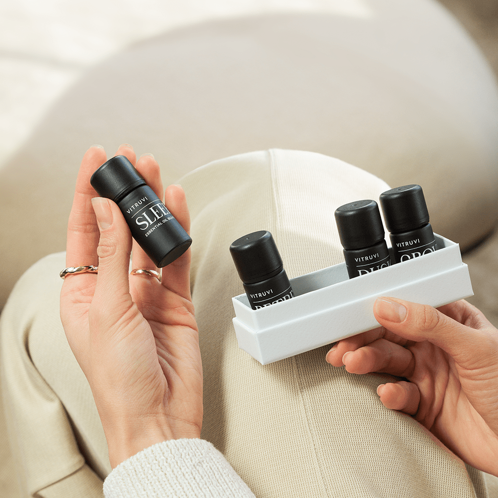 Person holding a set of black perfume bottles with a white tray against a neutral background