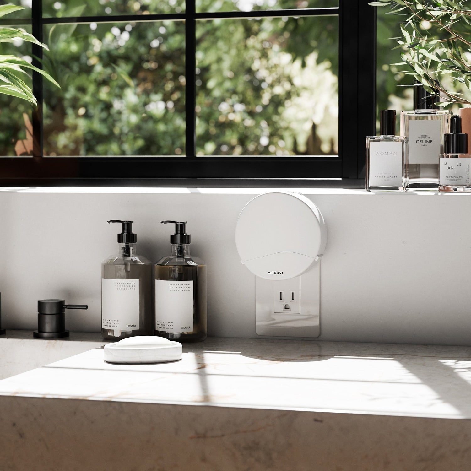 Bathroom counter with bottles, a mirror, and a window with greenery outside