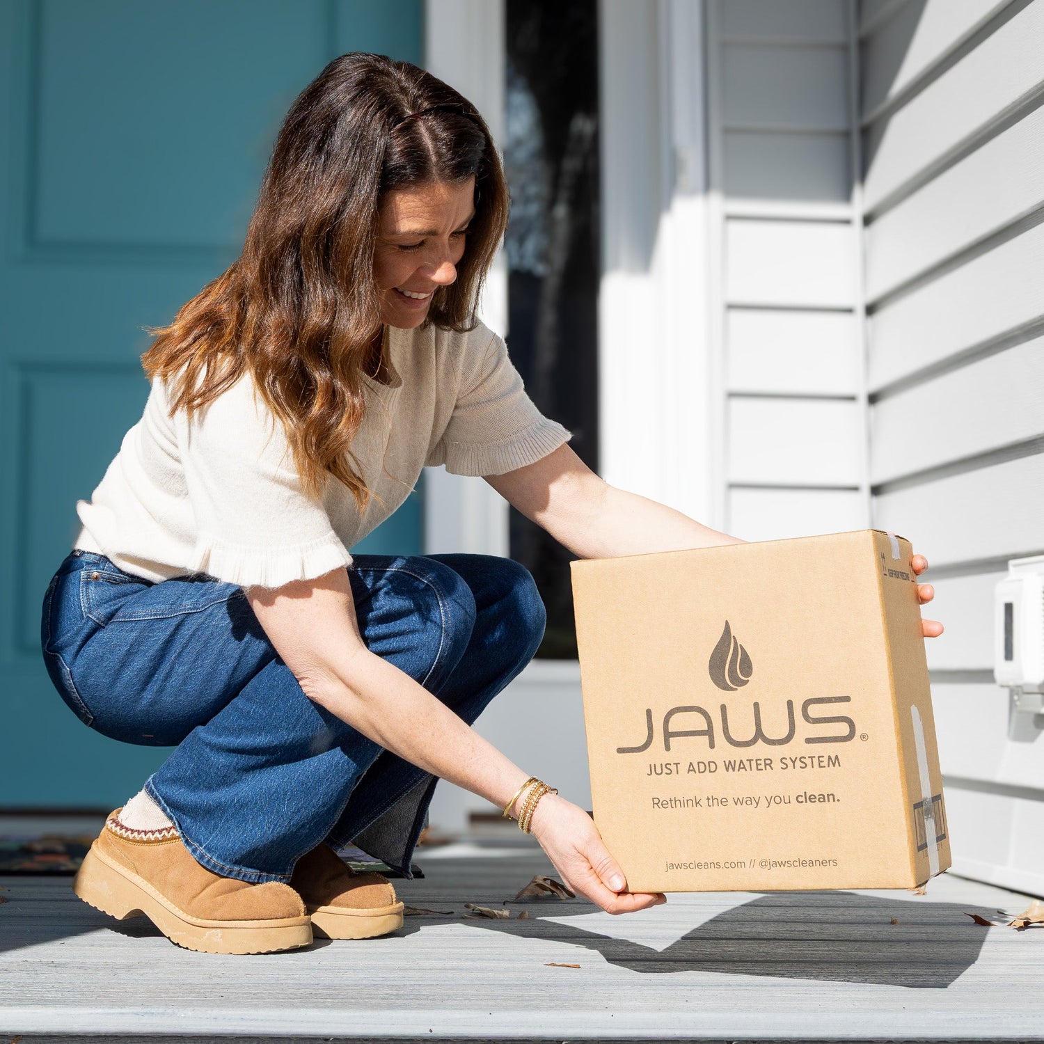 Woman unboxing a JAWS product box outside a house