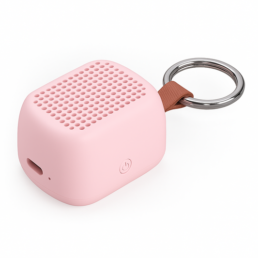 A small pink portable speaker with a brown fabric loop and a silver metal key ring, shown on a clean white background.